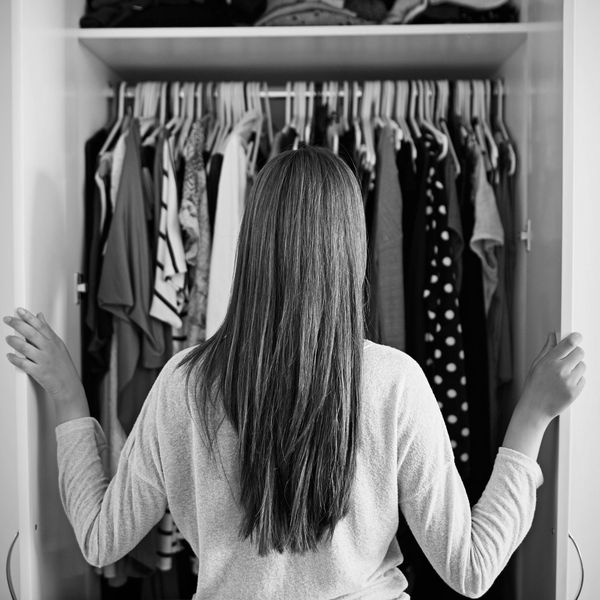 Woman with long hair looking at clothes in a closet.