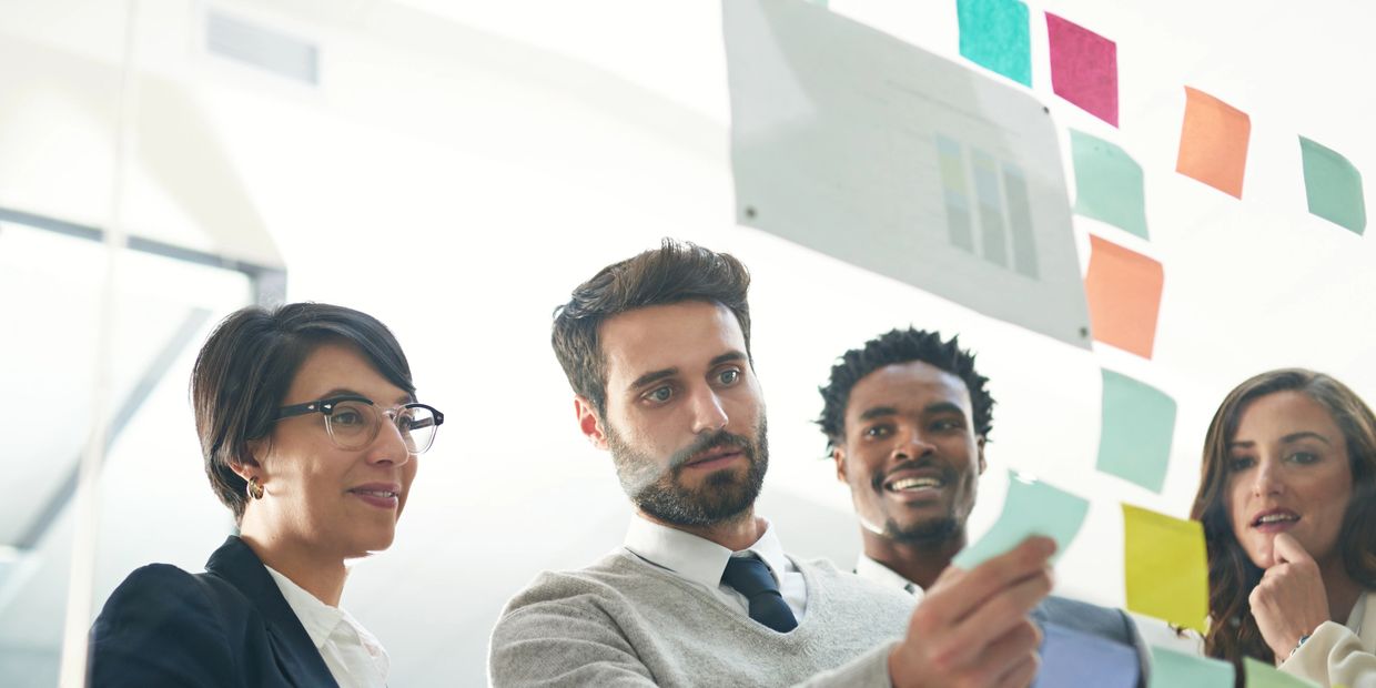 A group of professionals collaborating using sticky notes on a glass wall.