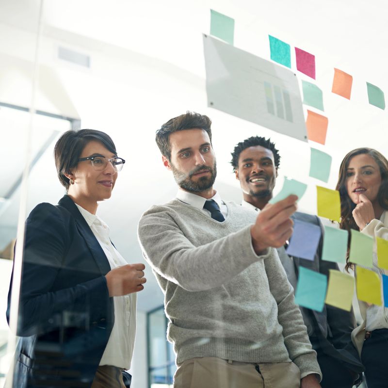 Shot of a group of businesspeople brainstorming on a glass wall in an office