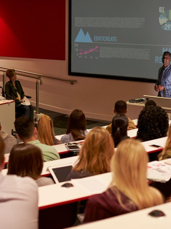A lecturer presenting market research data to students in a university classroom.