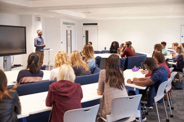 A man gives a presentation to a diverse group in a modern classroom.