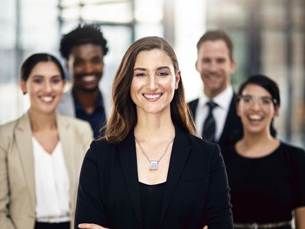 Confident businesswoman leading a diverse team with smiles.