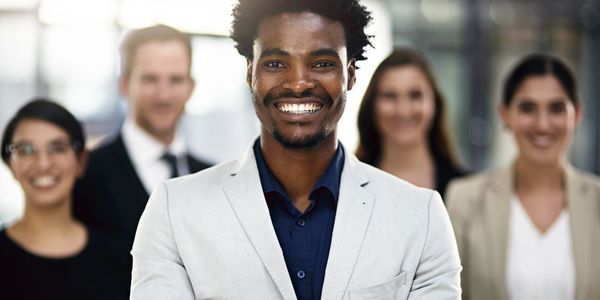 Confident businessman smiling with his diverse team in the background.