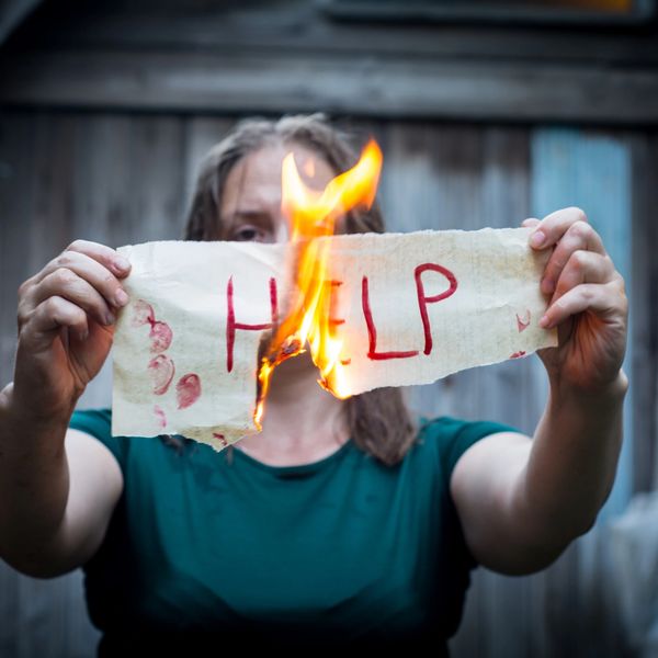 Person burning a 'HELP' sign.