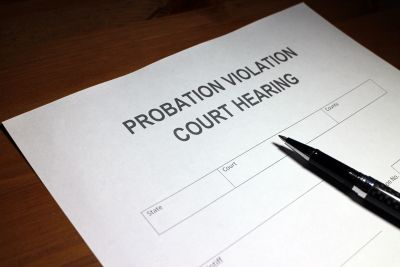 A probation violation court hearing document with a pen on a wooden surface.