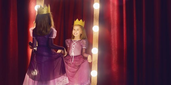Two girls in princess dresses and crowns having fun.