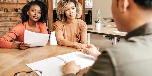 Two women attentively listen during a meeting with a man.