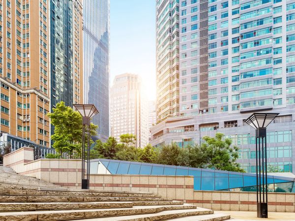 Modern cityscape with tall buildings and greenery under a clear blue sky.