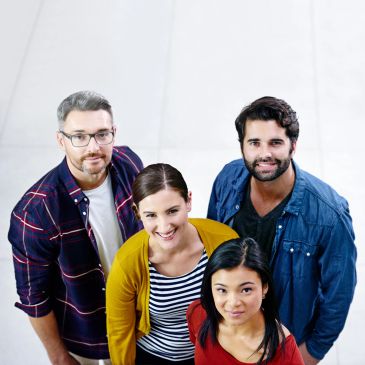 Four diverse adults smiling and looking up together.
