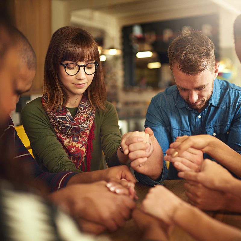 Shot of a group of people holding hands and praying together