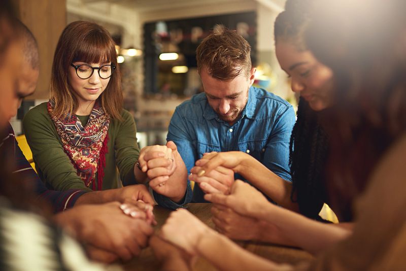 Shot of a group of people holding hands and praying together
