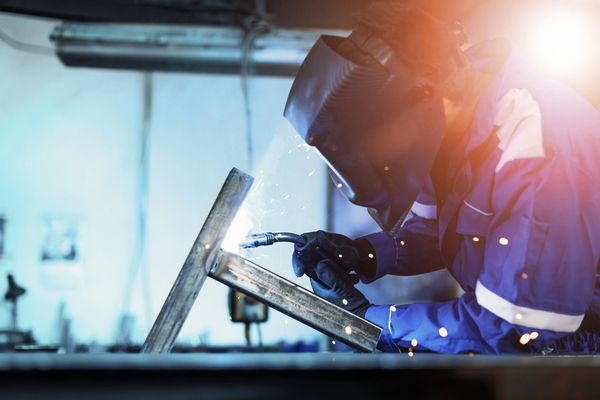Welder working on metal with bright arc sparks