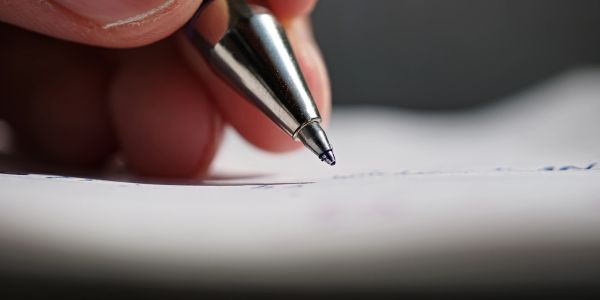 Close-up of a hand writing with a pen on paper.