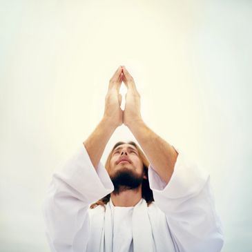 Man in white robe praying with hands raised towards the sky.