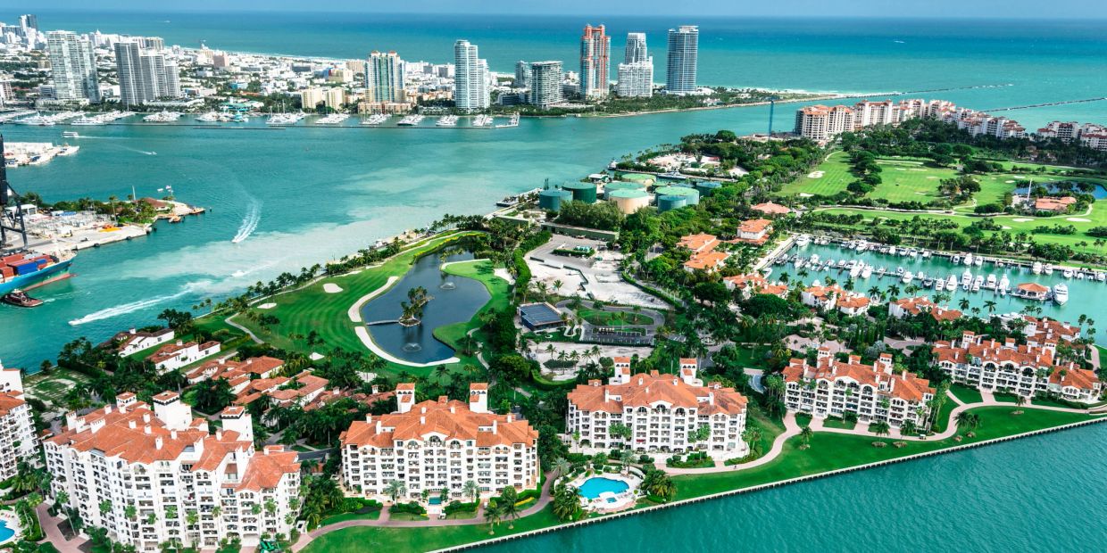 Aerial view of a coastal city with waterfront buildings and golf courses.