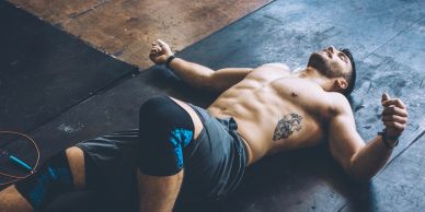 Exhausted man lying on the gym floor after workout.