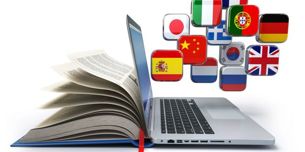 Laptop, book, and international flags representing language learning. Digital resources and courses 