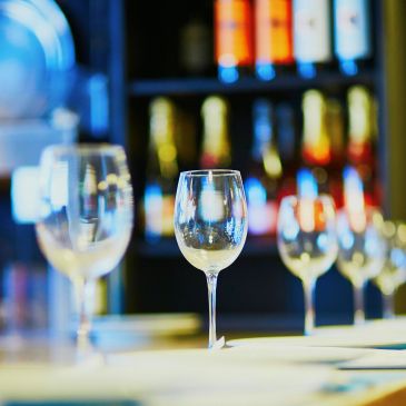 Empty wine glasses on a table with bottles in the background.