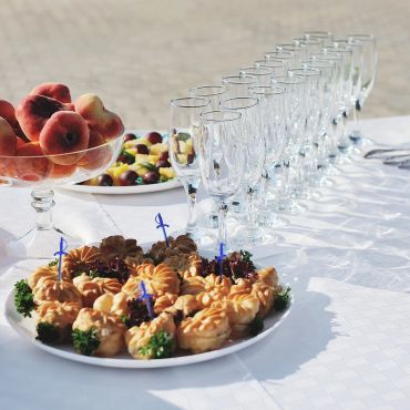 Appetizers, fruit, and empty glasses on a white tablecloth.