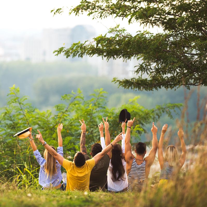 A group of friends raising their hands and chilling together in the outdoors.