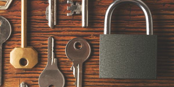 Various keys and a padlock on a wooden surface.