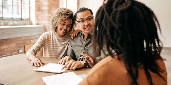 Couple discussing documents with a professional in a bright office.