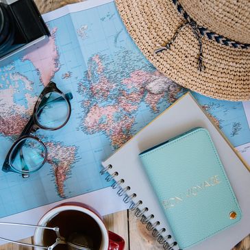 Travel essentials including a map, camera, glasses, hat, and tea.