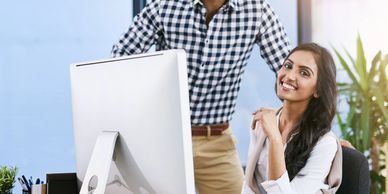 Two colleagues working together at a computer in a bright office.