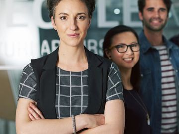 Confident businesswoman with colleagues in the background at the office.