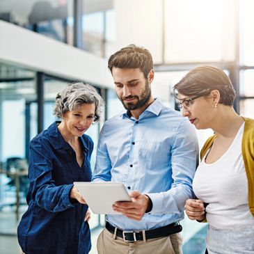 Three colleagues collaborating over a tablet in a modern office space.