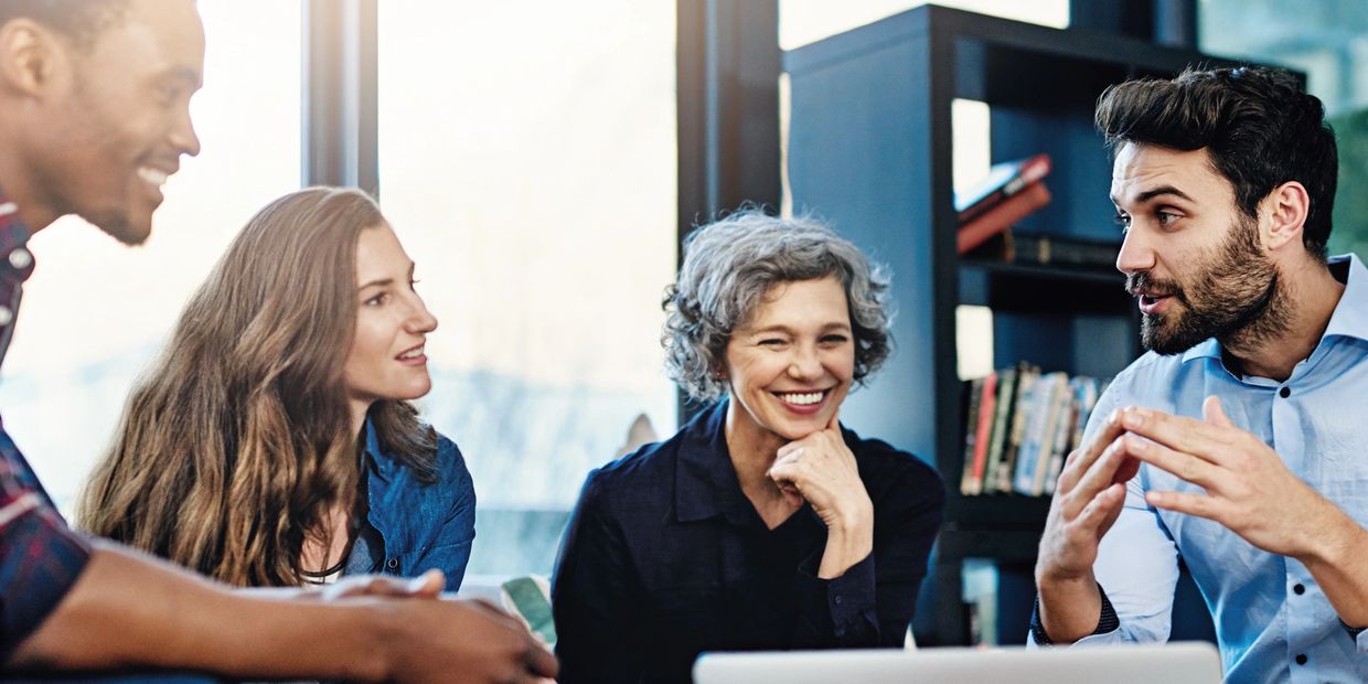 Four colleagues engaged in a lively discussion in a modern office space.