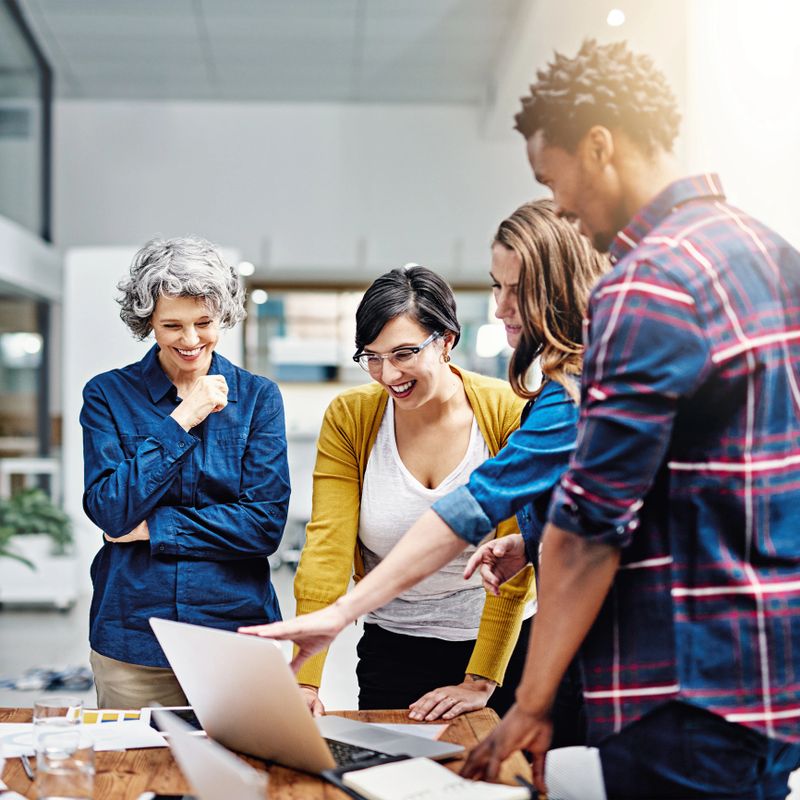 Cropped shot of a group of creatives working together on a laptop in a modern office