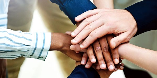 Diverse group stacking hands in unity and teamwork.