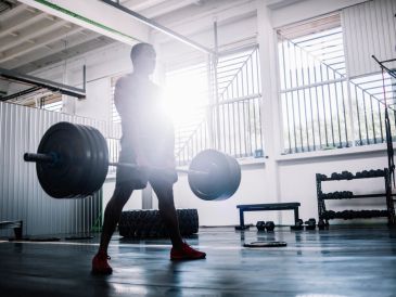 Man lifting heavy barbell in a gym.
