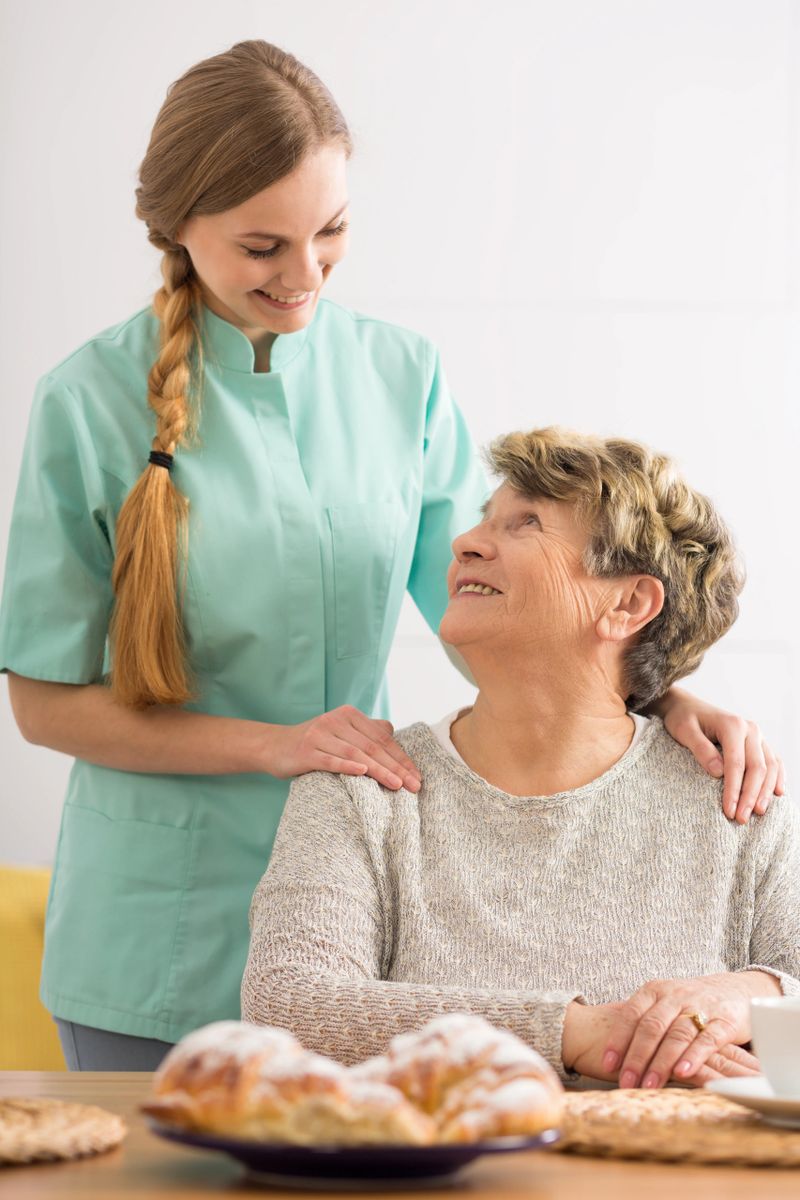 Portrait of an elderly woman and her home nurse standing behind her in an affectionate pose