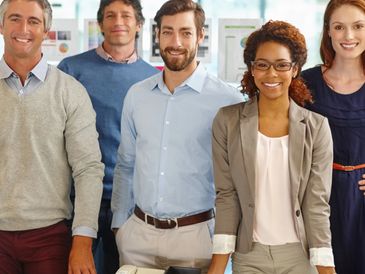 Diverse group of smiling professionals posing in an office environment.