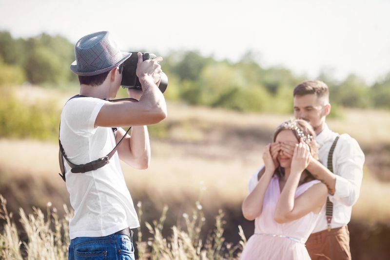 a wedding photographer takes pictures of the bride and groom in nature, the photographer in action