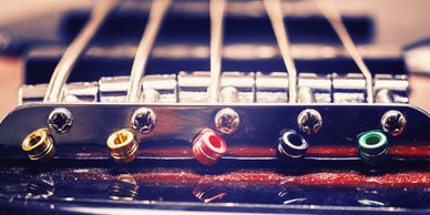 Close-up of guitar bridge with colorful string ends.