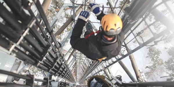 A man hanging from the side of a metal structure.