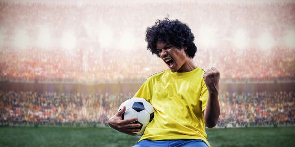 Excited soccer player celebrates with ball in stadium.
