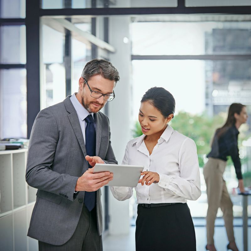 Shot of a businessman showing  something to his female colleague while they stand outside the boardroom