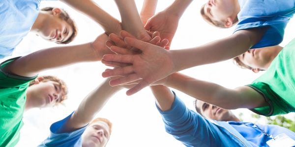 Group of people joining hands in teamwork gesture.