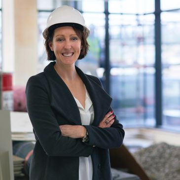 Confident woman engineer wearing a white hard hat and business attire.