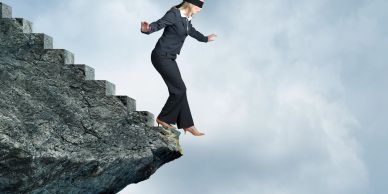 Blindfolded businesswoman about to step off a cliff.