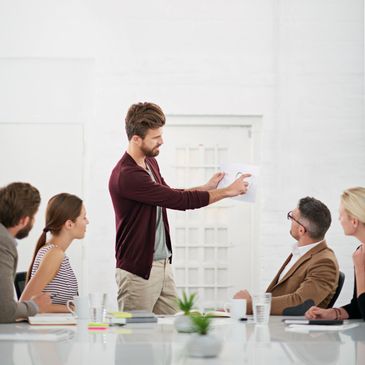 Man presenting ideas to colleagues in a modern office meeting.
