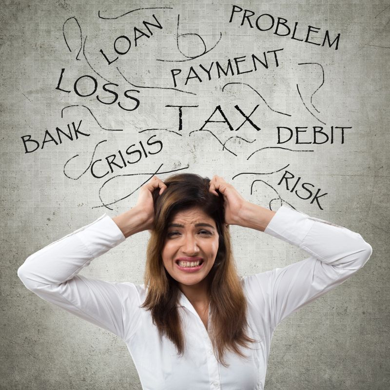 Frustrated young businesswoman wearing formalwear with text above his head such as loss, payment, loan, risk, crisis, debit, tax