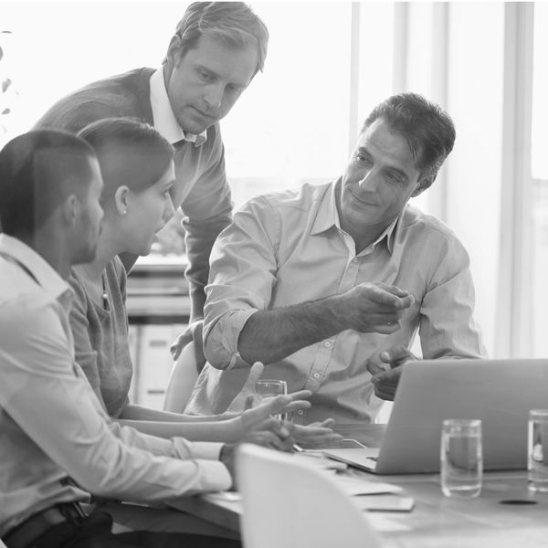 A group of professionals engaged in a discussion around a laptop.
