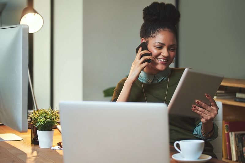 Shot of an attractive young woman using her cellphone and tablet in the office