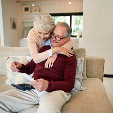 Smiling elderly couple reviewing finances together on a cozy couch.