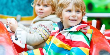 Two young boys enjoying a ride in a colorful amusement park car.